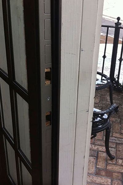 Aged bronze Door Armor jamb shield installed on a rental unit entry door